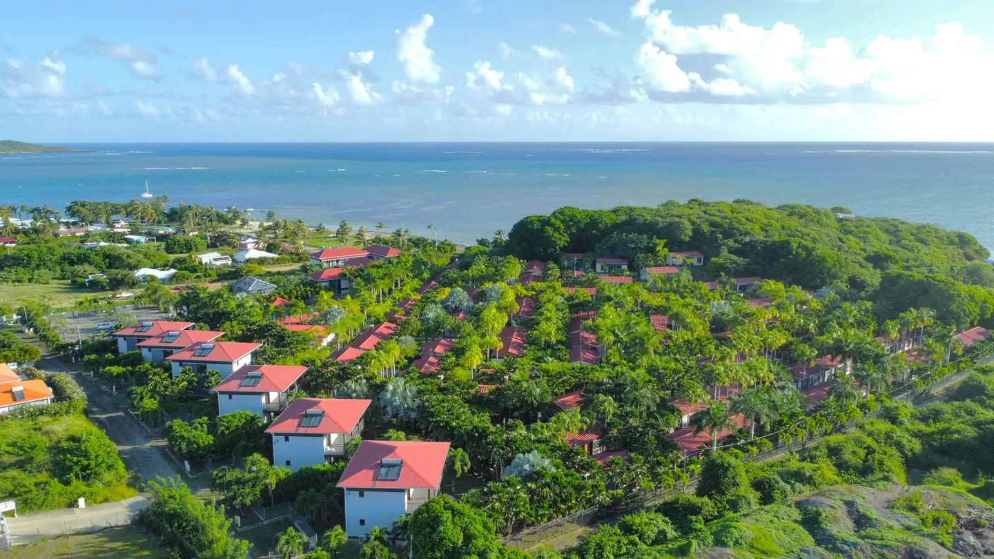 Vue aérienne du Village de la Pointe, ses toits rouges au milieu des palmiers et le lagon de la Pointe Faula